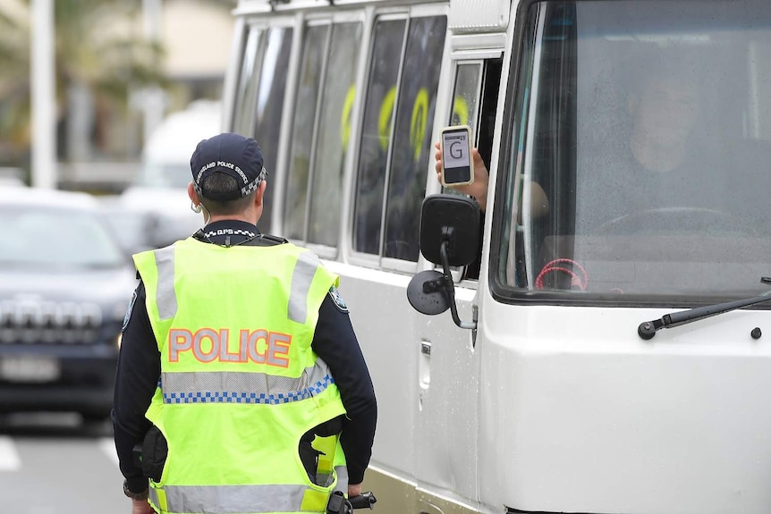 A driver from NSW displays his permit to Police at Griffith Street checkpoint at Coolangatta on the Gold Coast.