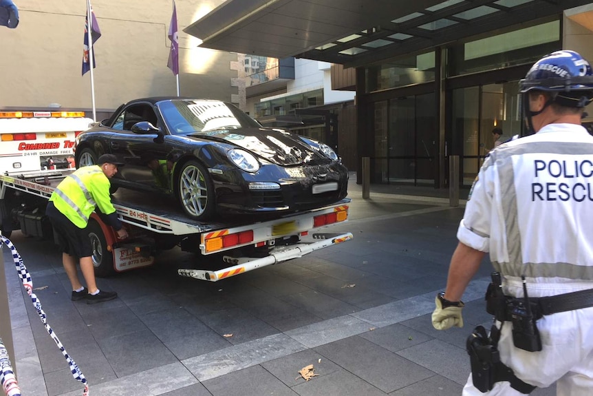 A sportscar on the back of a tow truck.