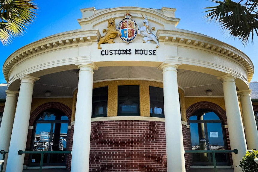 The exterior of an old building featuring colonial architecture, pillars and red brickwork.