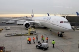 A twin-engined airliner in United livery is parked at an airport gate.