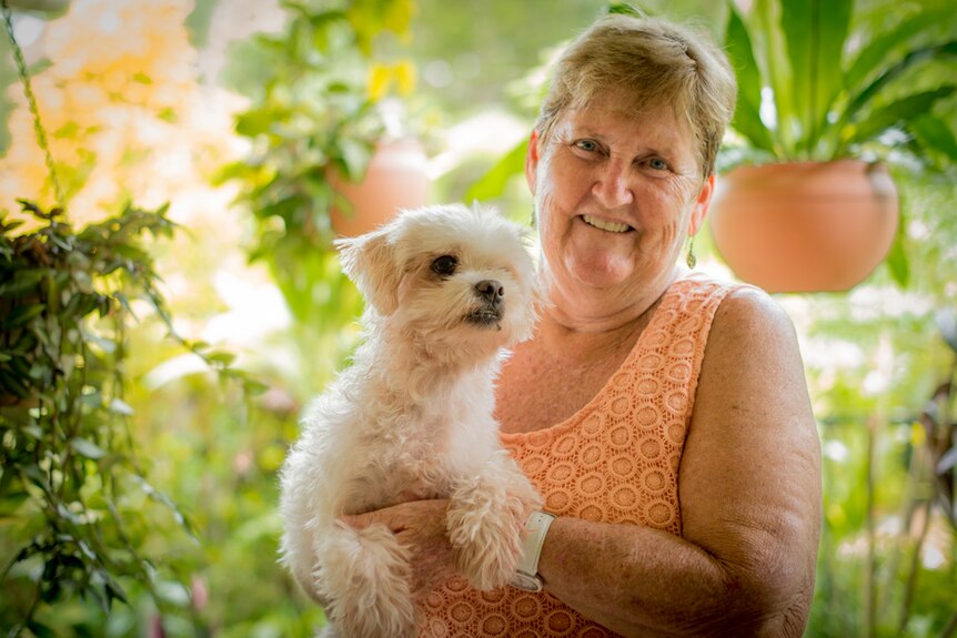 A woman holds a small white dog.