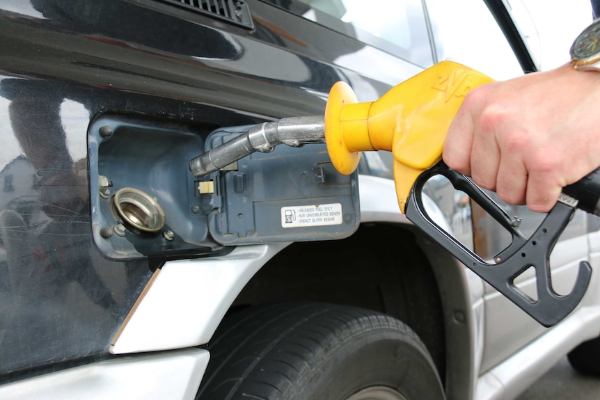 Hand holding petrol pump nozzle