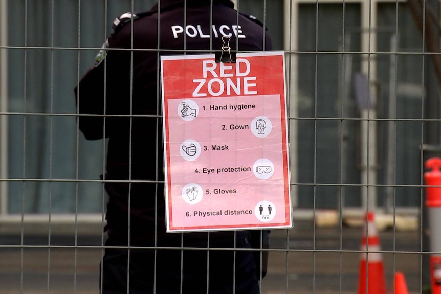 An SA Police officer stands next to a coronavirus warning sign outside the Pullman Adelaide.