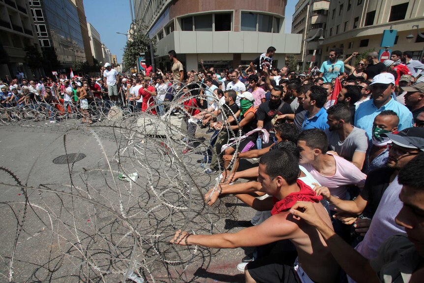 Lebanese protesters pull on barbed wire fences during a demonstration