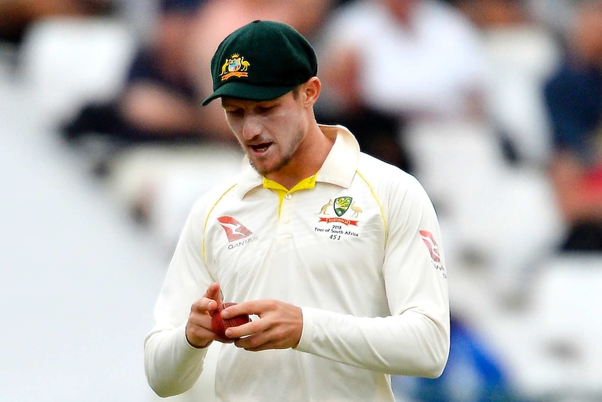 Telephoto shot of a cricketer shining a ball on his pants.