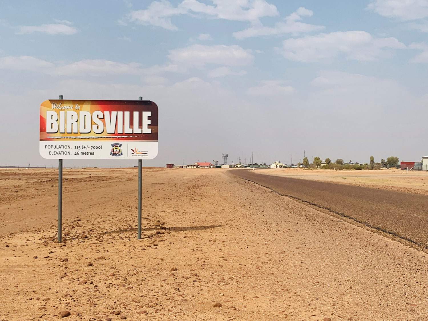A sign that says "Welcome to Birdsville" standing on the side of an outback highway.