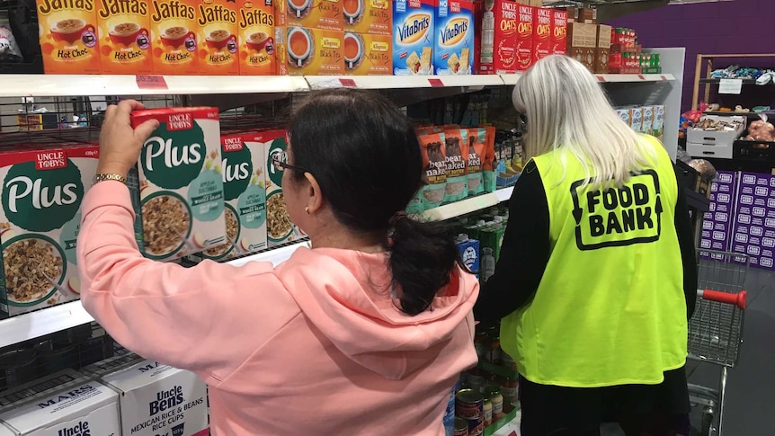 Two people grabbing products off a shelf at Foodbank SA