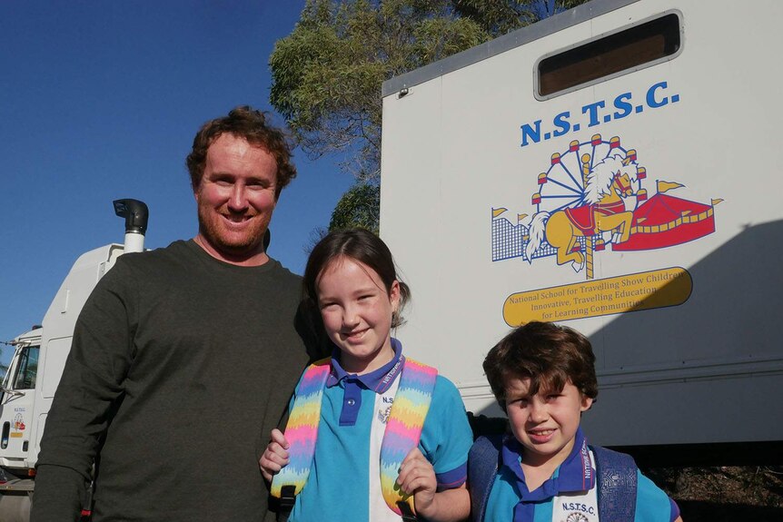 Boyd Baker, with his two children, stand beside the National School for Travelling Show Children truck classroom.
