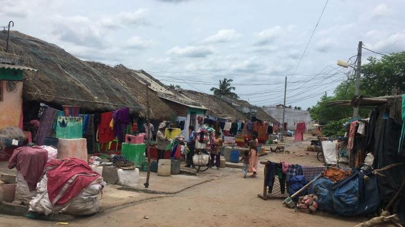 People walk in the streets of a poor slum street in India's Odisha state