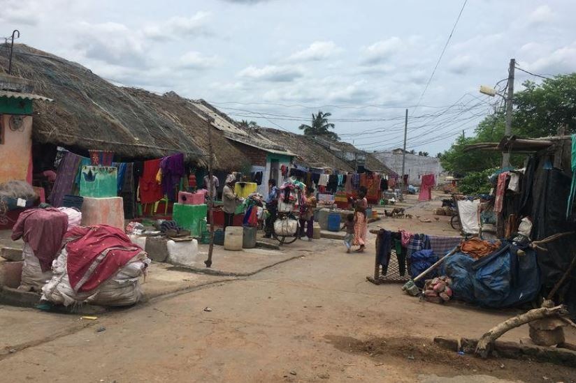 People walk in the streets of a poor slum street in India's Odisha state