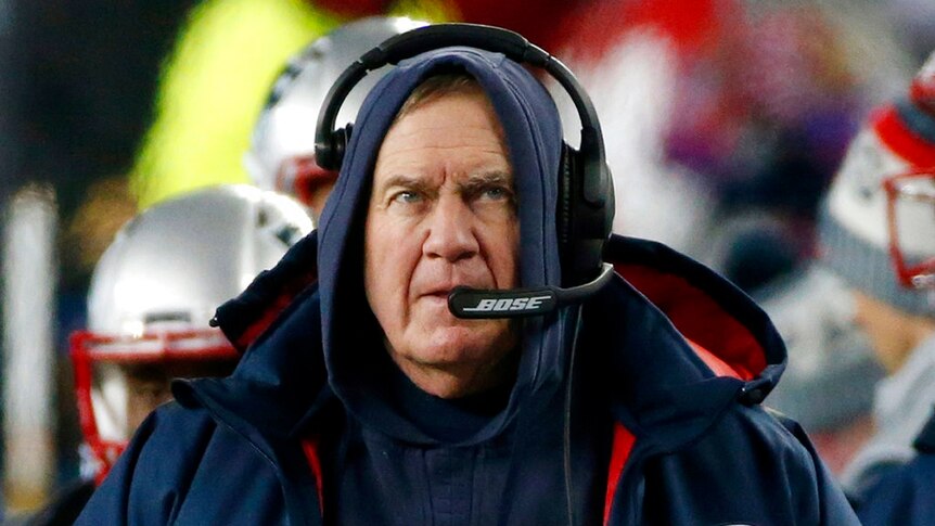 New England Patriots head coach Bill Belichick watches from the sideline wearing hood and headset
