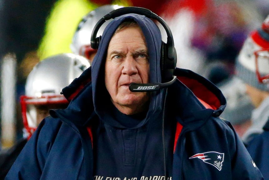 New England Patriots head coach Bill Belichick watches from the sideline wearing hood and headset
