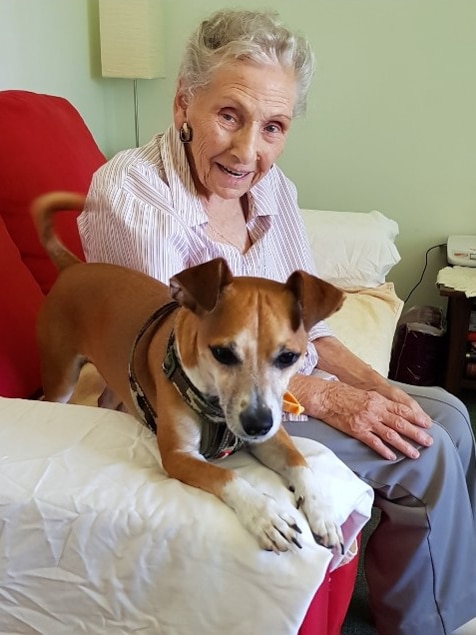 Older woman sitting on red sofa with dog