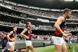 Essendon Bombers players run onto the MCG turf in front of a big crowd for their Anzac Day AFL game against Collingwood.