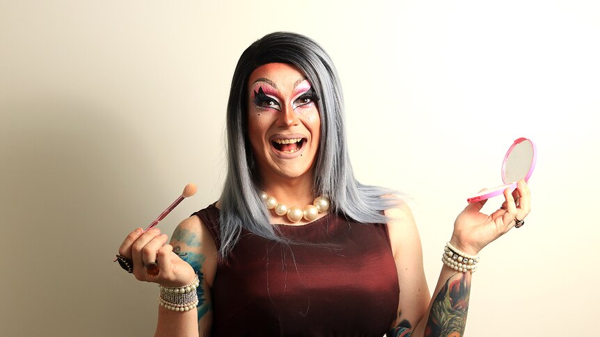 Wollongong drag queen Roxee Horror applies makeup and smiles.