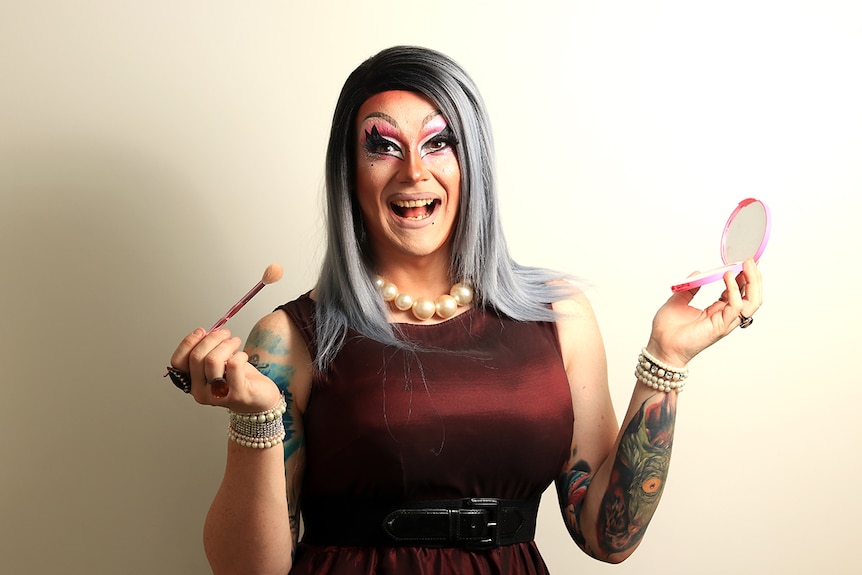 Wollongong drag queen Roxee Horror applies makeup and smiles.