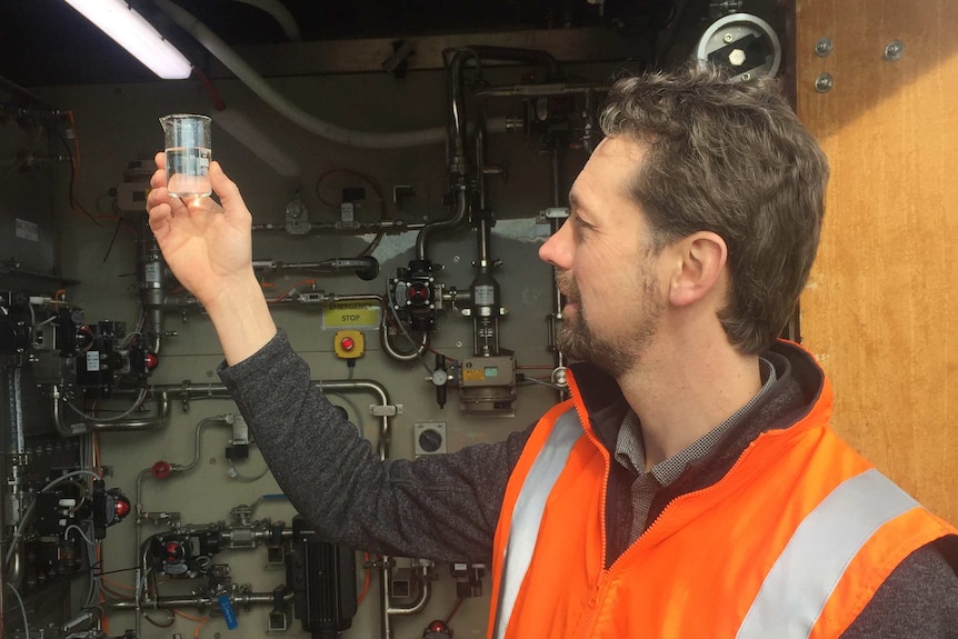 Australian Antarctic Division engineer Michael Packer holding treated water sample.