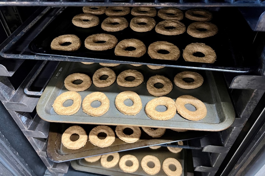Doughnut shaped cookies on trays in an oven.