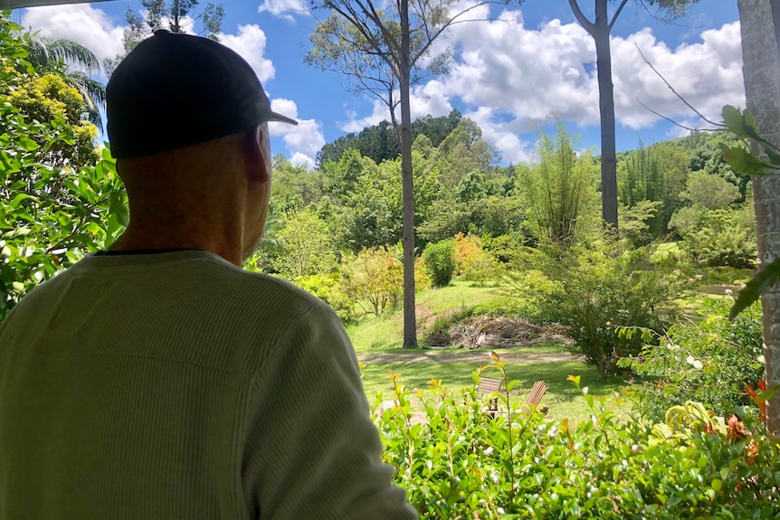 A man looks out over a lush property.