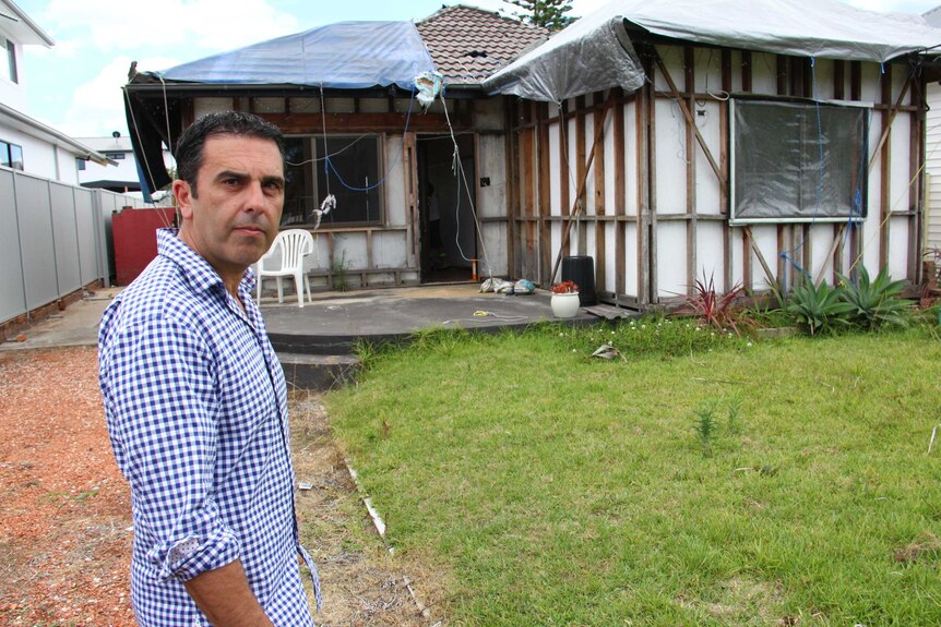 Sutherland Mayor Carmelo Pesce stands in front of a tornado-damaged home.