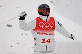 Australia's Cooper Woods grins widely and brandishes his ski pole in delight after the end of a men's mogul run in Beijing.