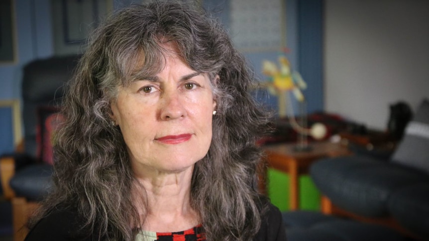 A woman with wavy dark hair holds a serious and focused gaze towards the camera.