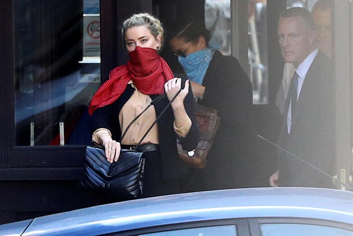 Actor Amber Heard is pictured arriving to court before the trial with a red scarf covering her nose and mouth.