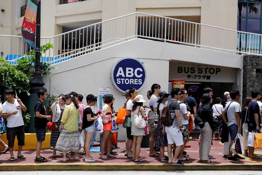 Tourists queue outside a bus stop on the island