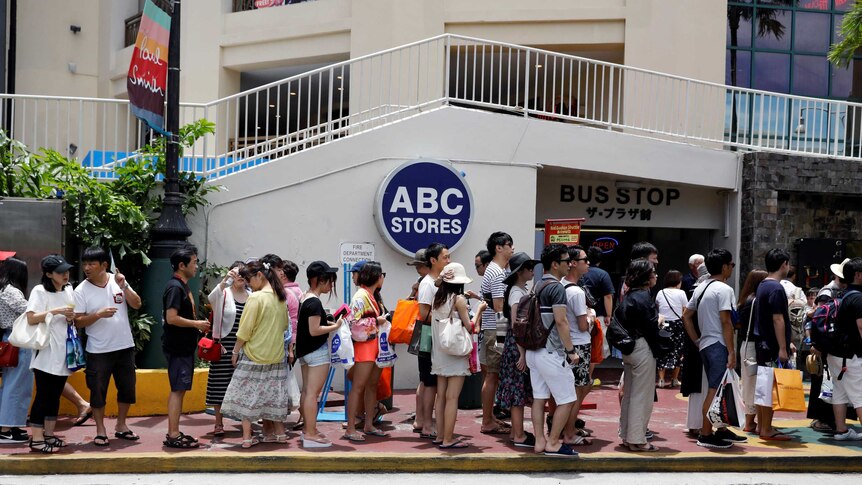 Tourists queue outside a bus stop on the island