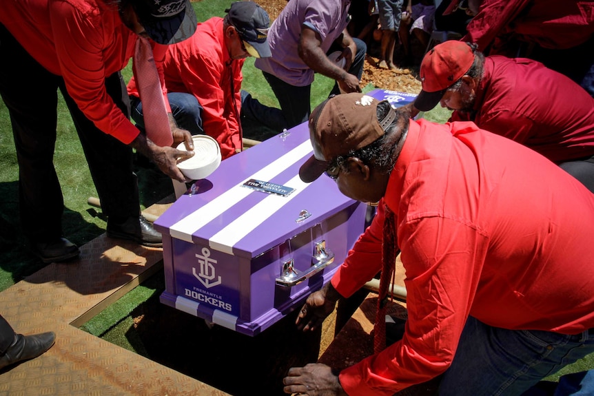 Image of pallbearers laying Alexsandra Hall's coffin in the ground.
