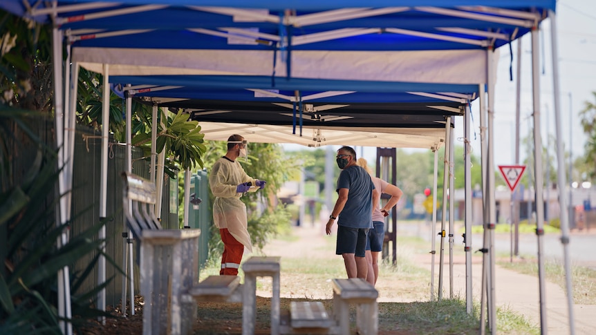 Two men talking under a marquee outside a COVID-19 testing centre.