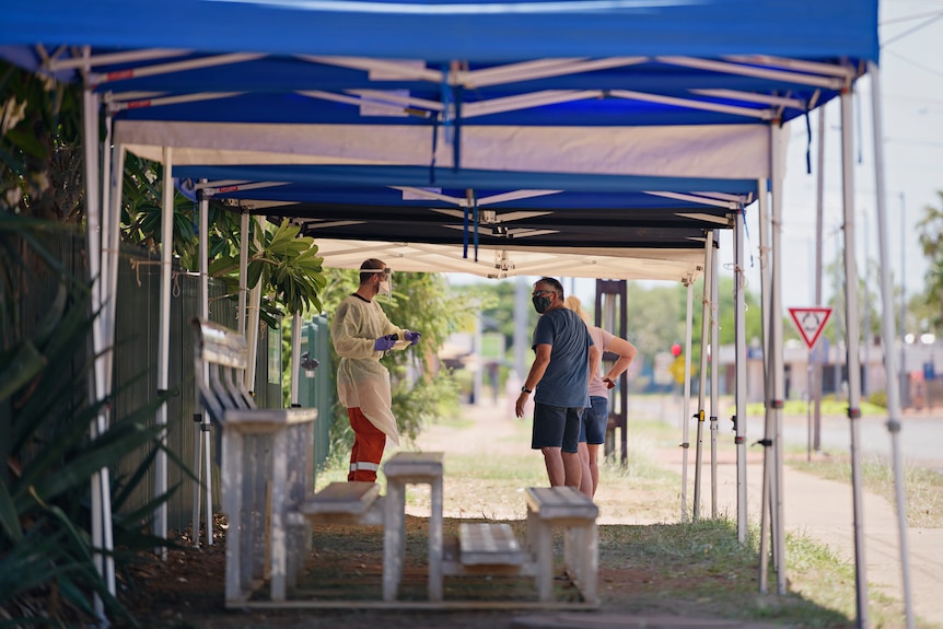 Two men talking under a marquee outside a COVID-19 testing centre.