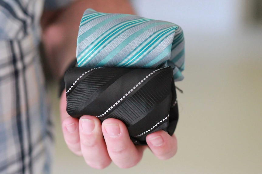Folded neckties held in a hand.