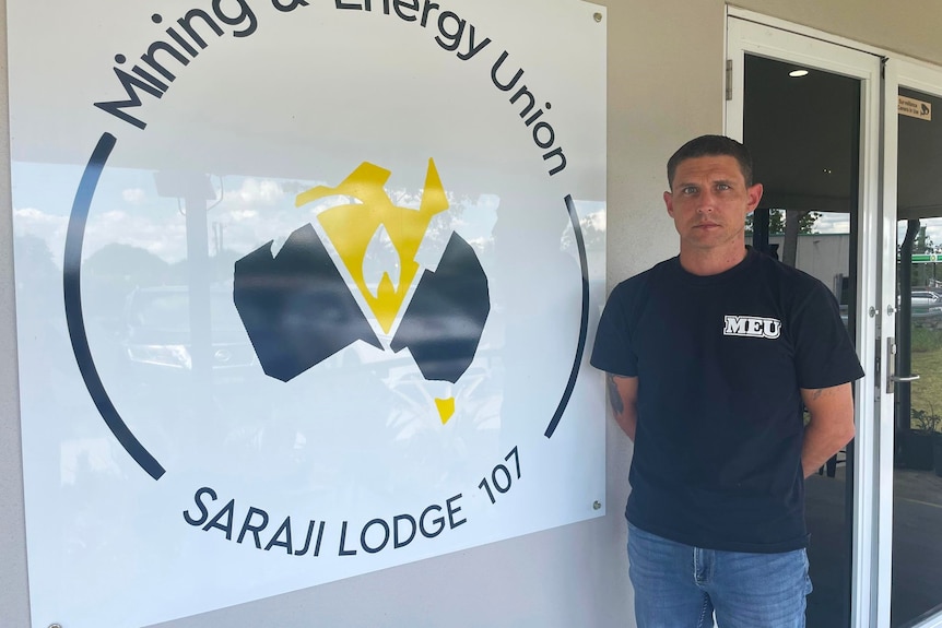 A man stands unsmiling in front of a sign reading 'mining and energy union Saraji Lodge 107'