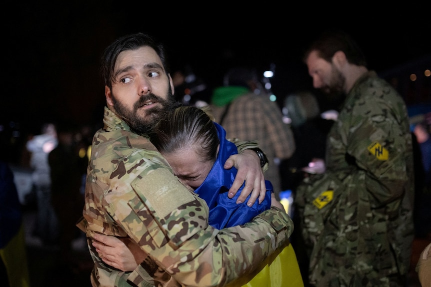A Ukrainian prisoner of war hugs another person.