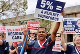 Nurses hold up signs and chant outside a hospital