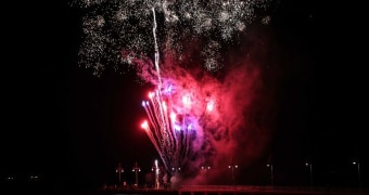 Pink and red fireworks shoot up against contrasting black sky along Perth's waterfront.