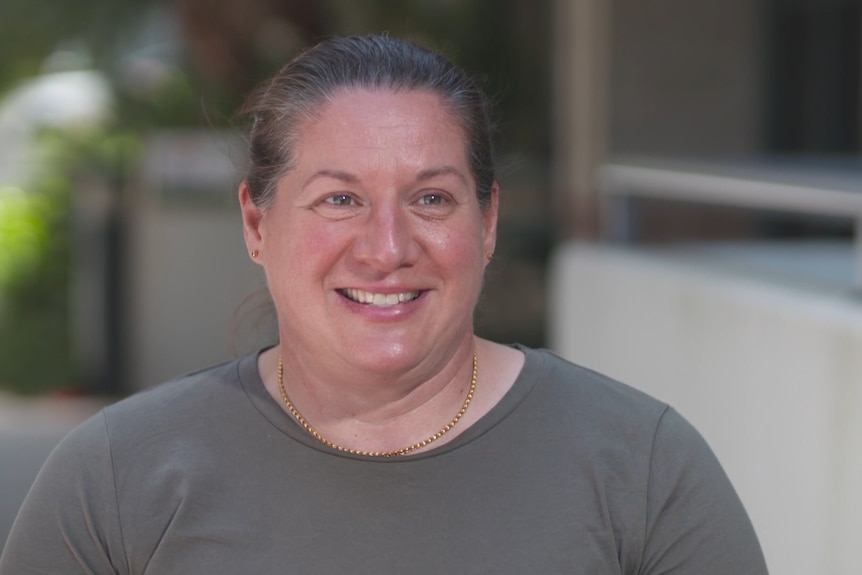 Louise Sauvage vêtue d'une chemise grise et souriante. 