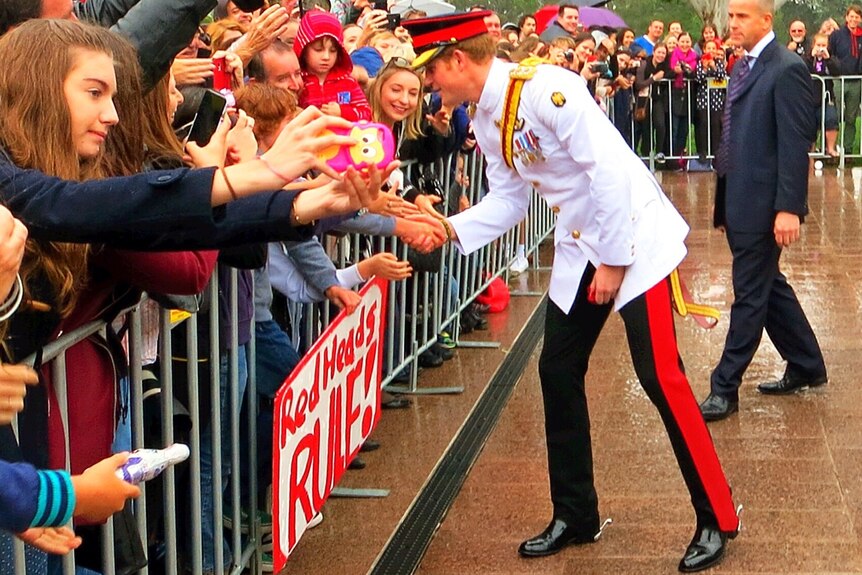Prince Harry shakes a child's hand in the crowd in Canberra.