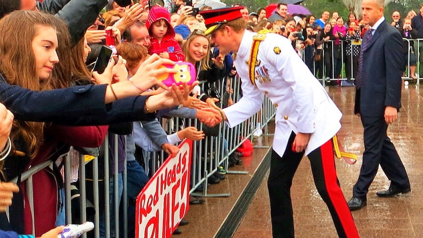 Prince Harry shakes a child's hand in the crowd in Canberra.