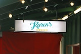 A photo of Karen's Diner logo on a sign hanging from a green roof in front of the restaurant