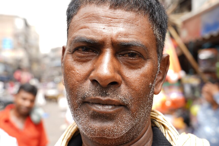 An Indian man looking exhausted on a busy  street 