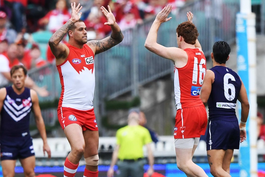 Gary Rohan and Lance Franklin with the arms raised about to the embrace as they celebrate a goal.