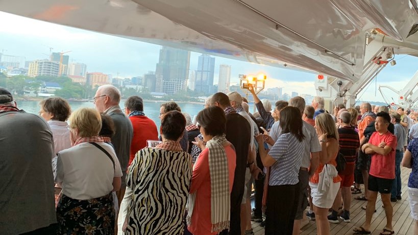 Passengers on a cruise ship as it arrives at a Cambodian port.