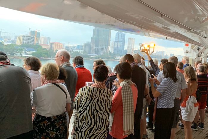 Passengers on a cruise ship as it arrives at a Cambodian port.