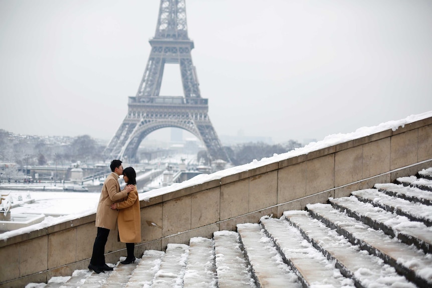 A couple kiss in front of the Eiffel Tower in Paris on February 7, 2018.