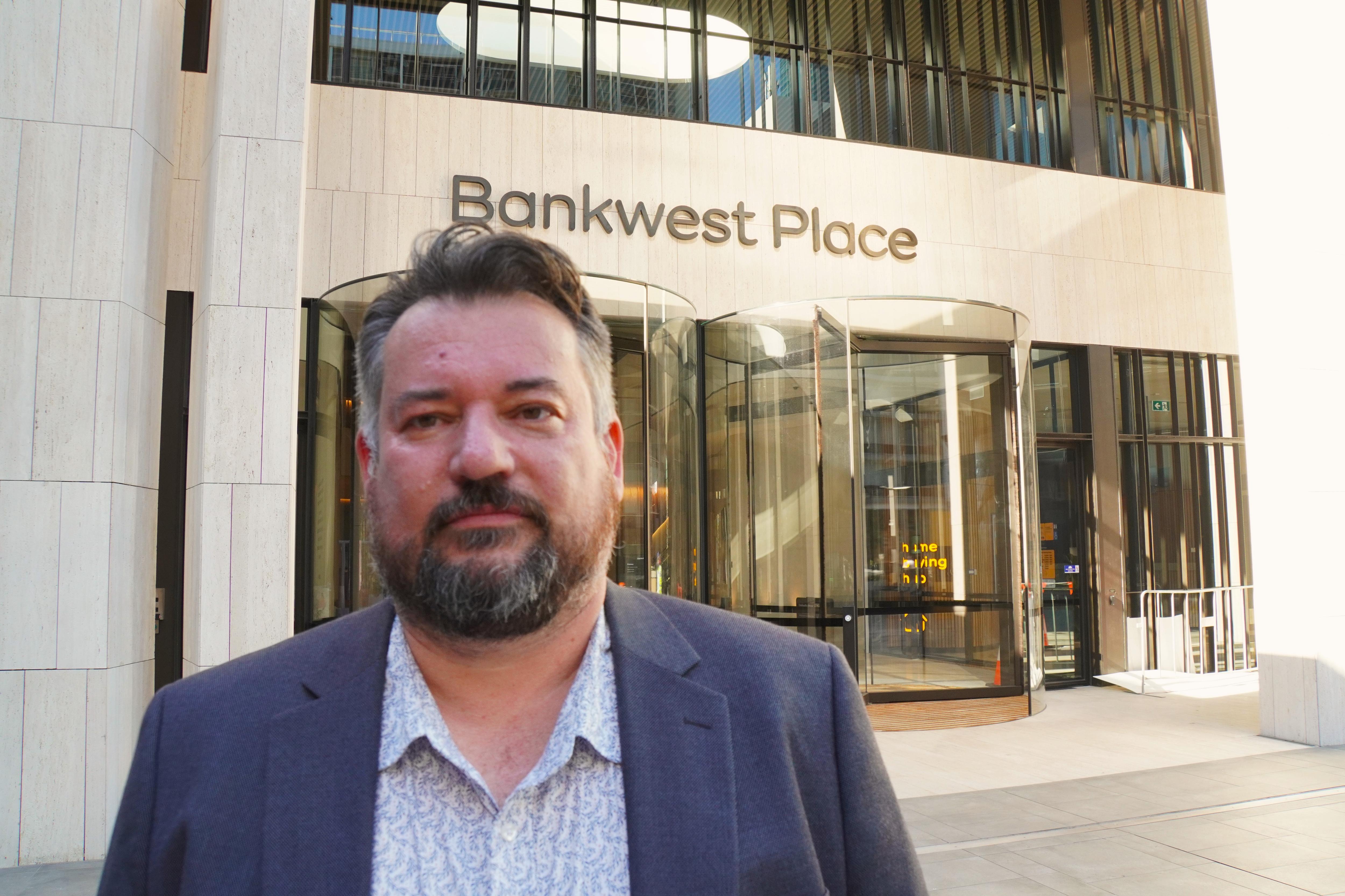 Un hombre barbudo llamado Jason Hall parece serio mientras mira a la cámara. 