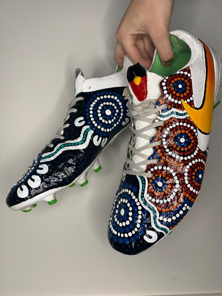 A pair of football boots with Aboriginal art painted on them. 