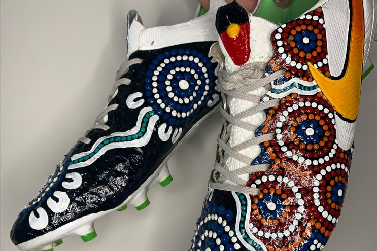 A pair of football boots with Aboriginal art painted on them. 