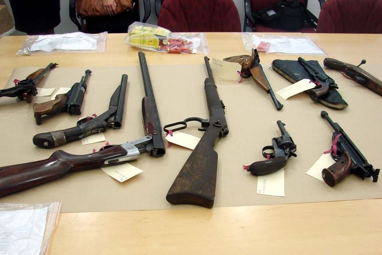 Firearms and ammunition are displayed to the media